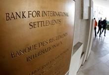 People walk past a sign in front of the Bank For International Settlements (BIS) in Basel 